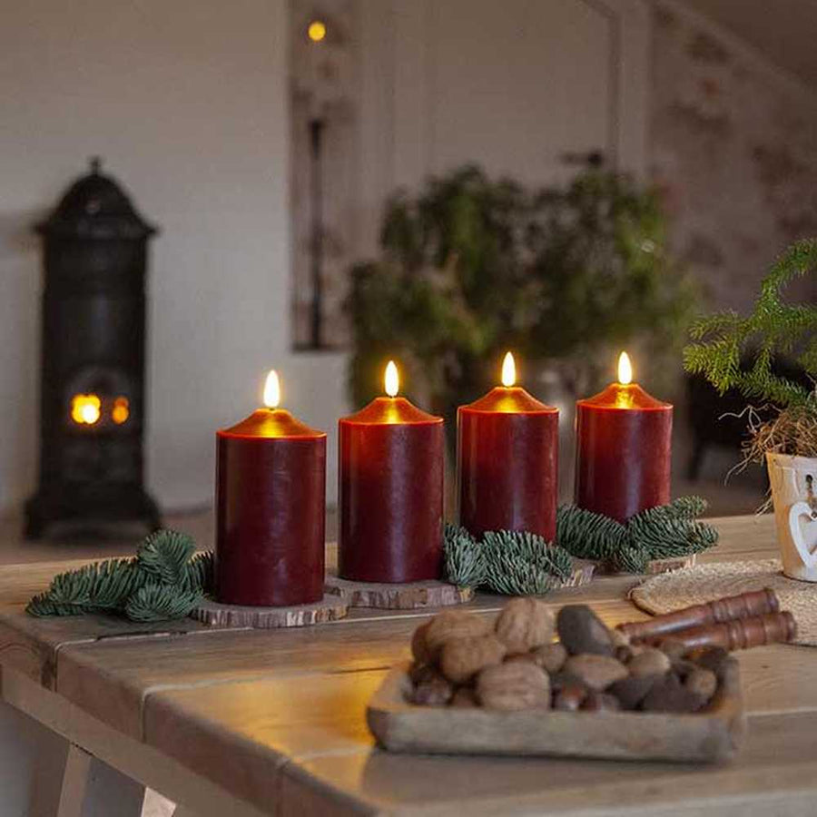 Bordó színű karácsonyi led gyertyák fa a asztalon, fenyőágakkal 