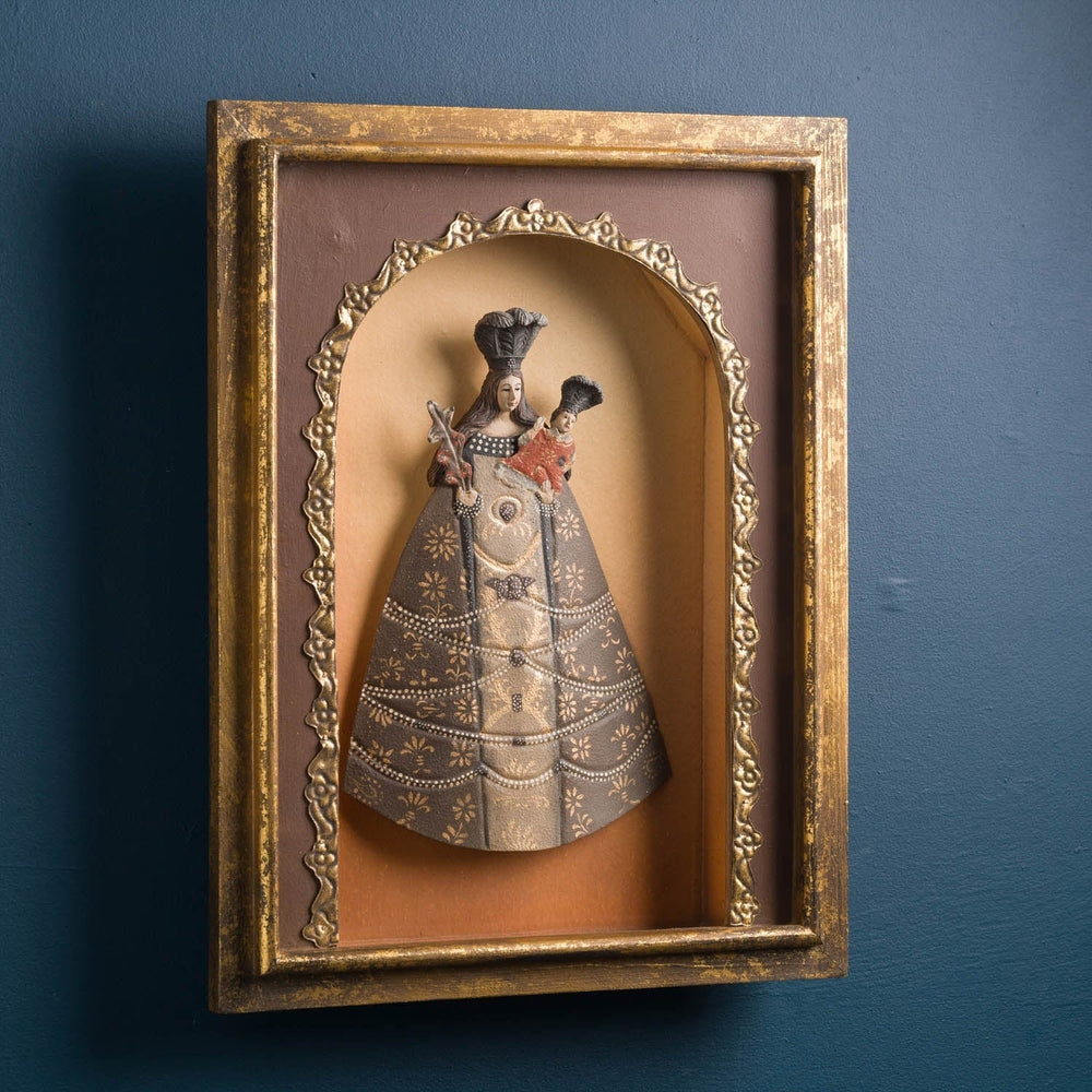 Szoborfülkés fa képkeretbe foglalt, a Liliomos Madonnát ábrázoló figura.