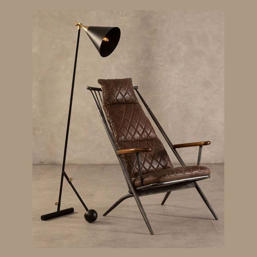 Vasból készült, vintage sötétbarna színű marhabőrrel kárpitozott, kortárs-loft stílusú, formatervezett prémium pihenő karosszék, állólámpával modern bemutatóteremben. 