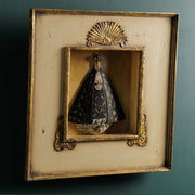 Szoborfülkés fa képkeretbe foglalt, a Magányos Szűzanyát ábrázoló figura.