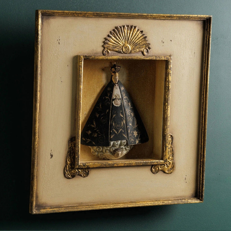 Szoborfülkés fa képkeretbe foglalt, a Magányos Szűzanyát ábrázoló figura.