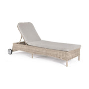 Vidéki vintage stílusú, kerekekkel felszerelt,, dönthető háttámlájú, natúr színű műrattan napozóágy, bézs színű olefin fekvőpárnával,