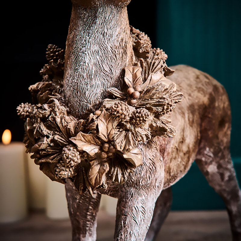 Erdei fenyőtoboz koszorúval díszített, nagyméretű karácsonyi szarvas figura..