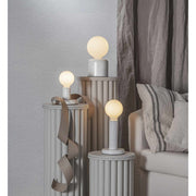 Asztali lámpák posztamenseken, matt felületű opál LED izzókkal.