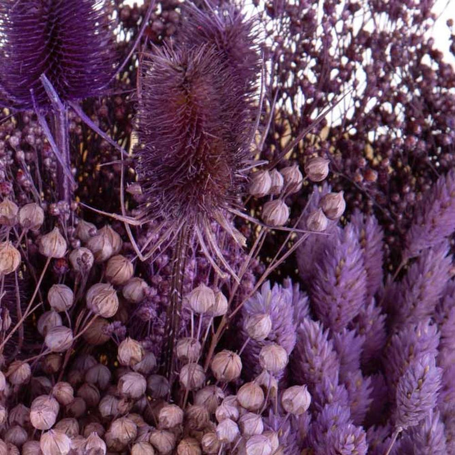 Natúr színű papírba csomagolt, 30 cm átmérőjű és 50 cm magas, vegyes kialakítású lila színű szárított gyógynövénycsokor