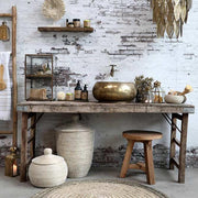 Tropical, illetve modern Art Deco stílusú függeszték lámpa, antikolt réz színű, áttört mintázatú fém levelekkel, enteriőrben bútorokkal, fehér téglafal előtt