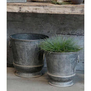 Vintage bádog kaspó szett, zöld fűvel szürke fal előtt.