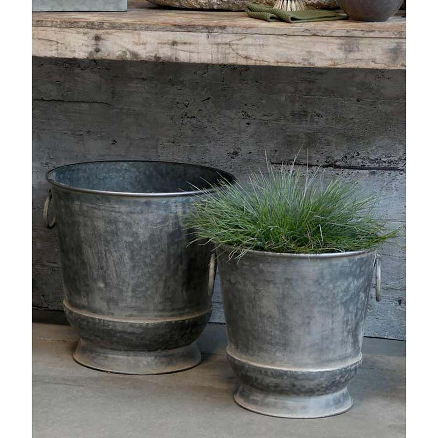Vintage bádog kaspó szett, zöld fűvel szürke fal előtt.