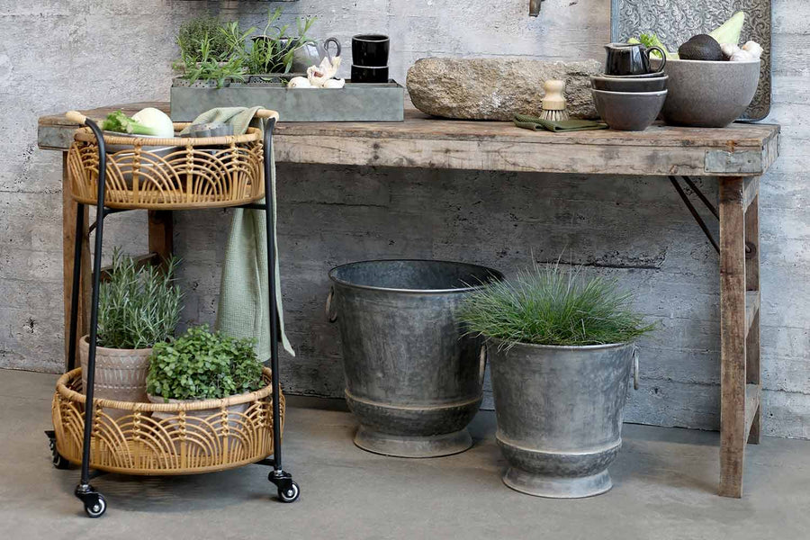 Rusztikus fa asztal bádog kaspókkal és gurítható bambusz asztalkával.