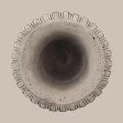 Antikolt felületű, szürke színű talpas cement kaspó.