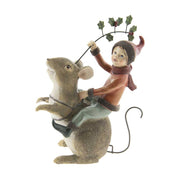 Barna színű erdei egér hátán utazó karácsonyi manó bordó ruhában és sállal, kezében magyallal 