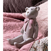 Vintage stílusú, enyhén kopott, antik krém színű, ülő helyzetű nosztalgikus maci figura, púderrózsaszín színű masnival a nyakában