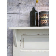 Krém színű falipolc zöld üvegvázával. 