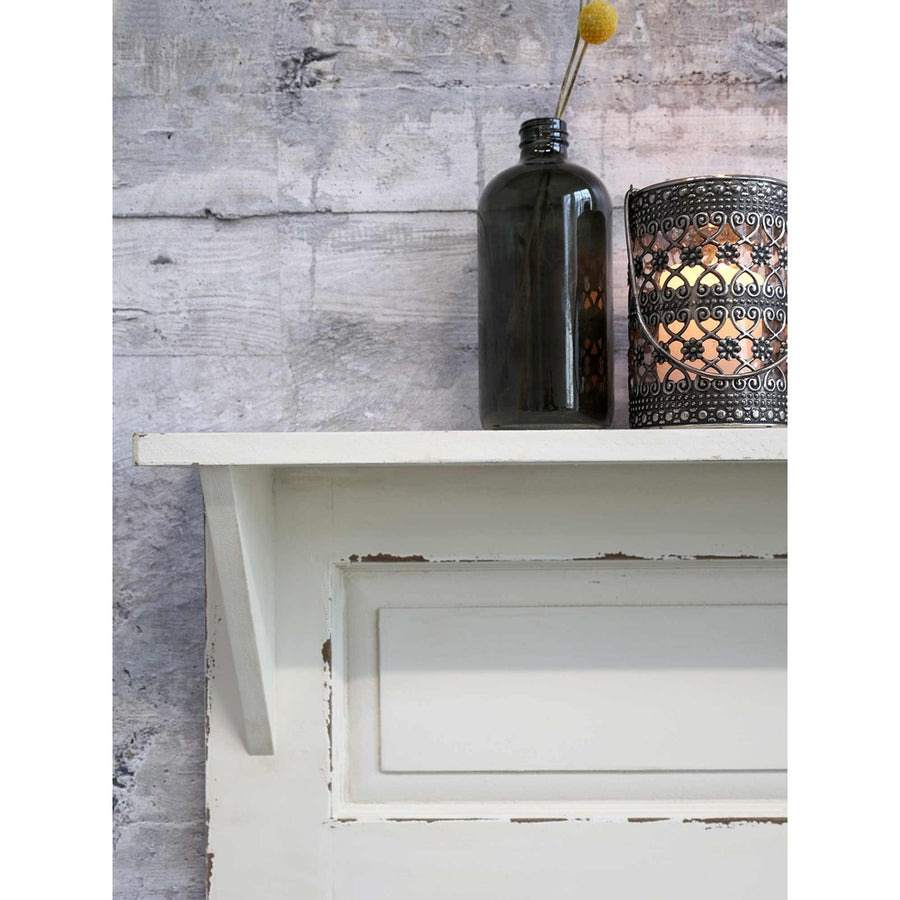 Krém színű falipolc zöld üvegvázával. 